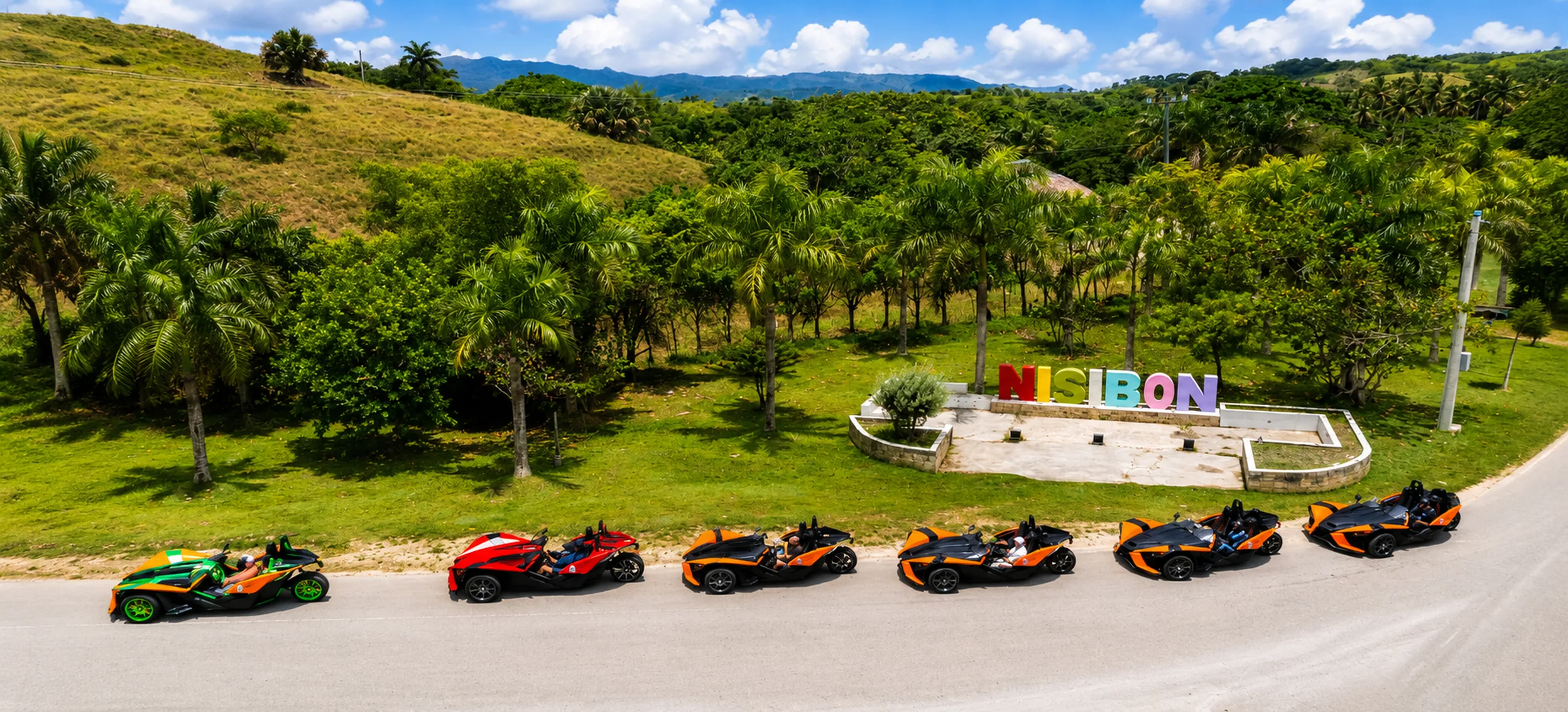 Aerial view of a Polaris Slingshot convoy parked beside the colorful Nisibón sign during a guided Punta Cana Slingshot adventure through the Dominican Republic