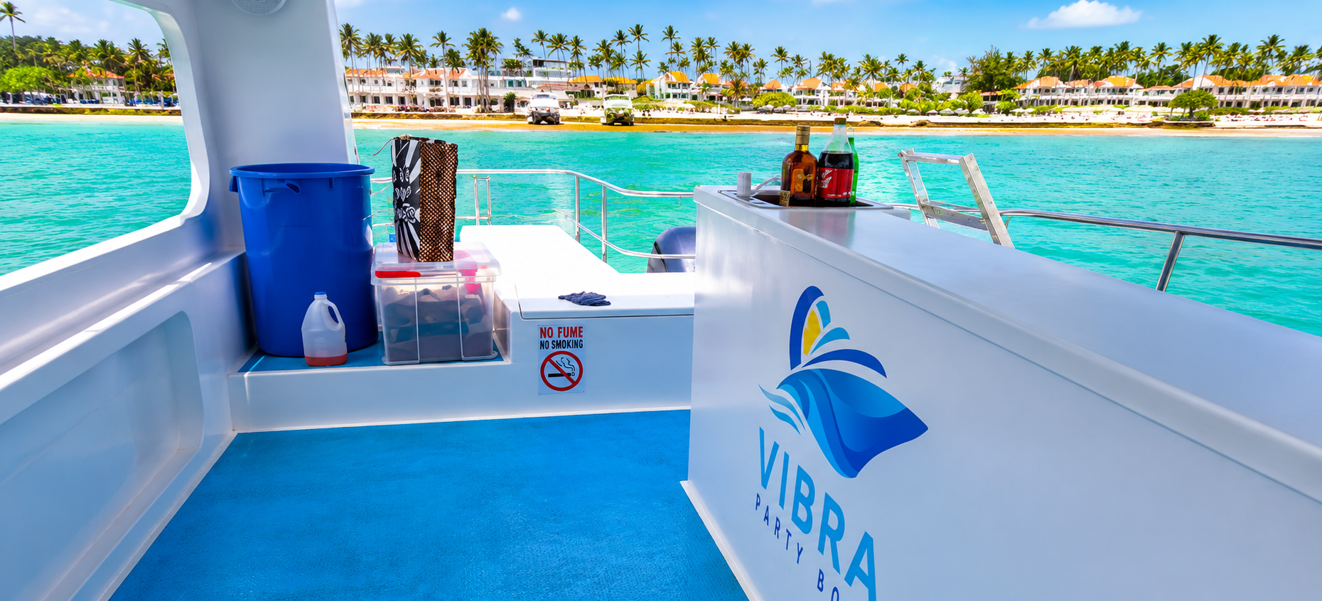 Interior bar area of the Vibra Bávaro Party Boat overlooking the turquoise Caribbean Sea and the palm-lined coastline of Punta Cana.