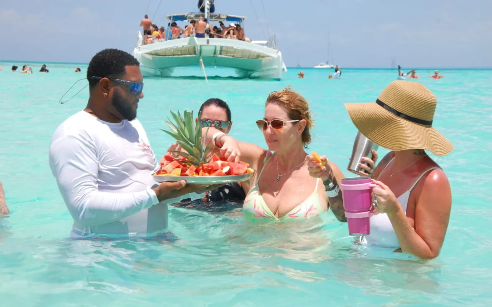 Private Saona Island catamaran guests enjoying tropical fruit and drinks in the turquoise Natural Pool.