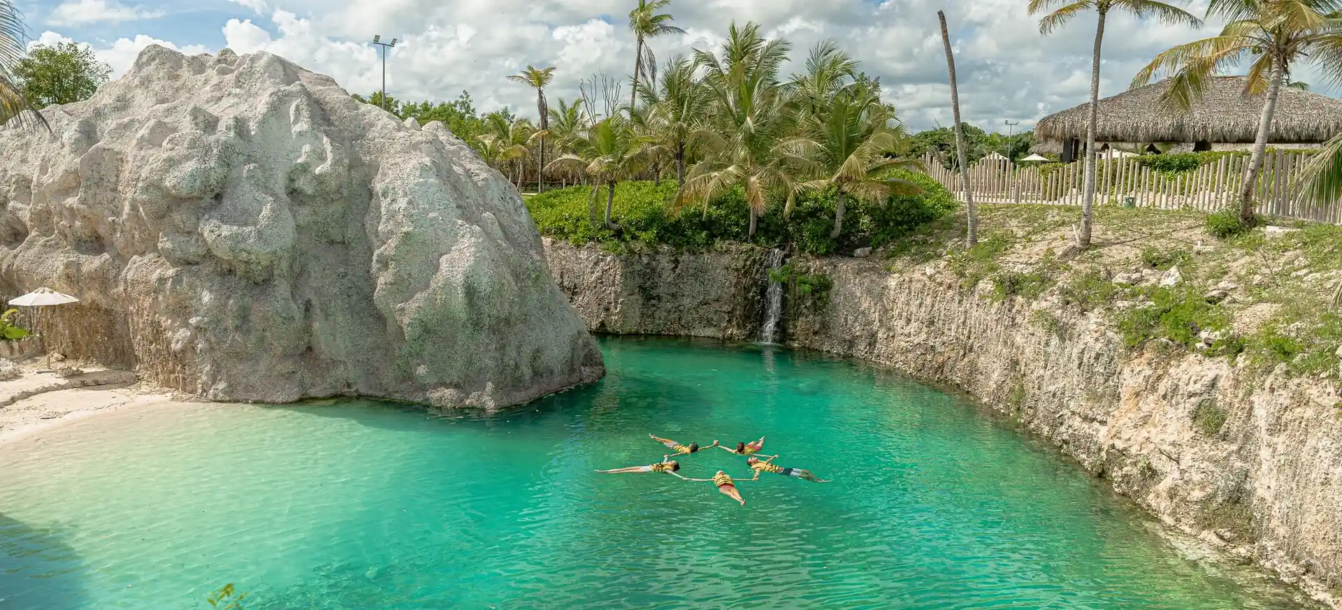 Natural turquoise lagoon surrounded by rock cliffs and palm trees at El Dorado Park.