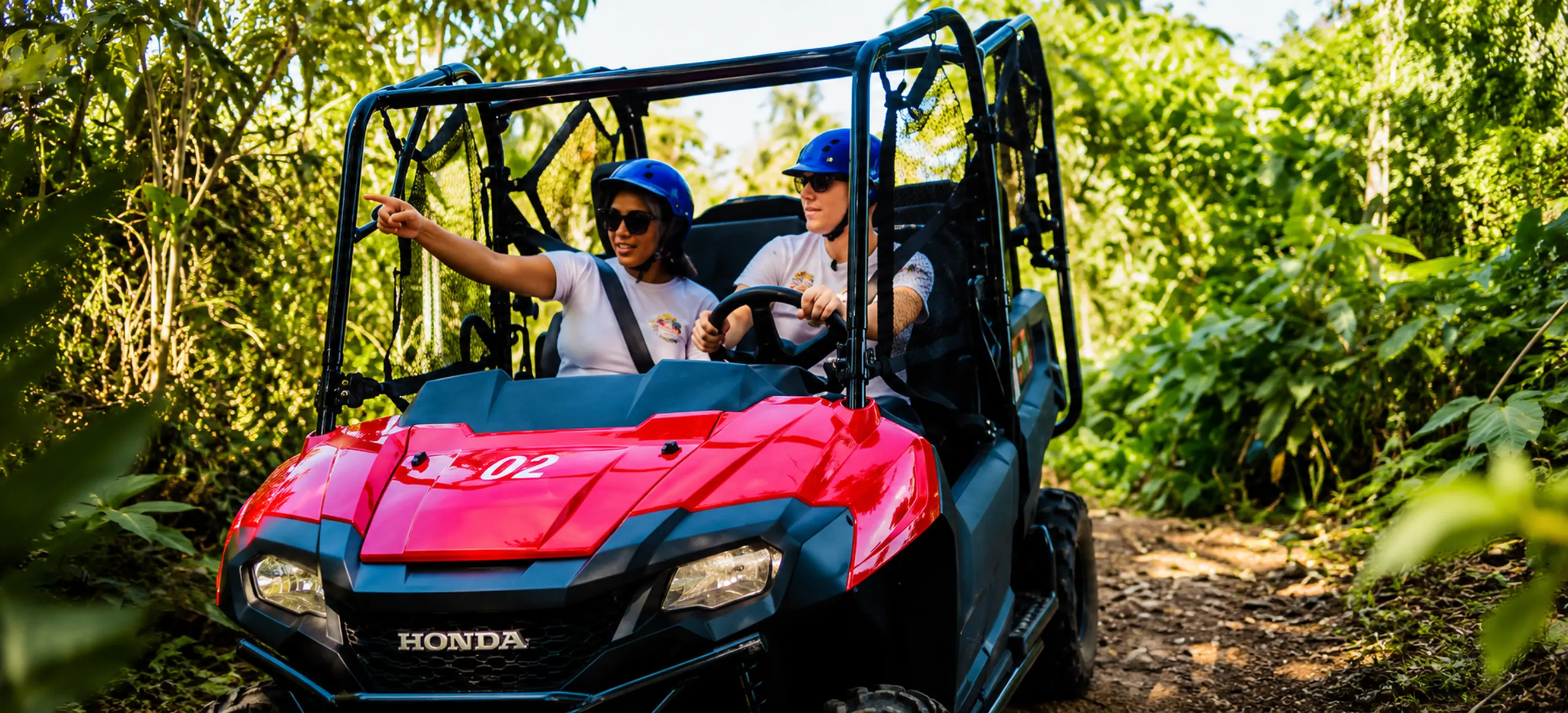 Couple riding a red UTV through tropical jungle on Monkeyland buggy tour in Punta Cana