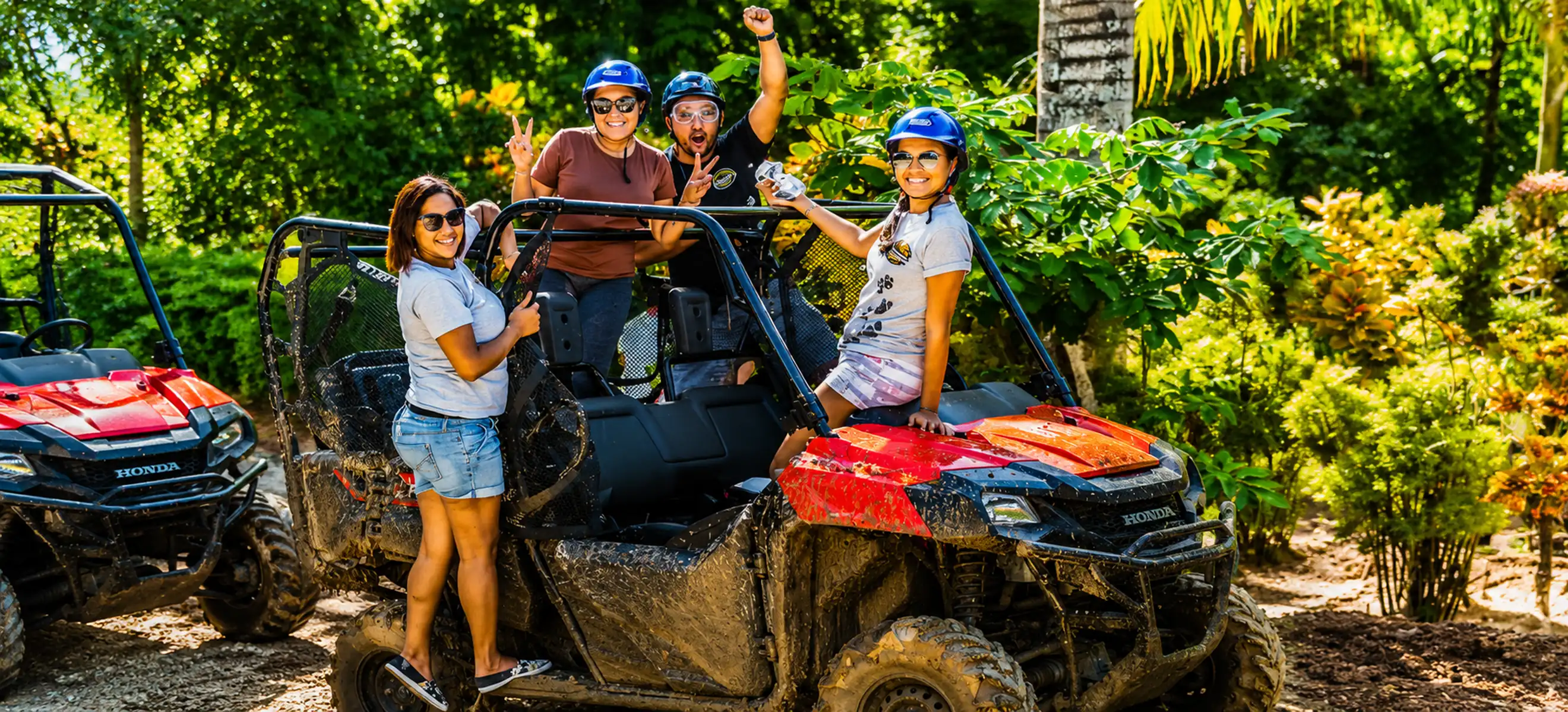 Group of friends celebrating beside muddy UTVs on Monkeyland jungle buggy adventure in Punta Cana