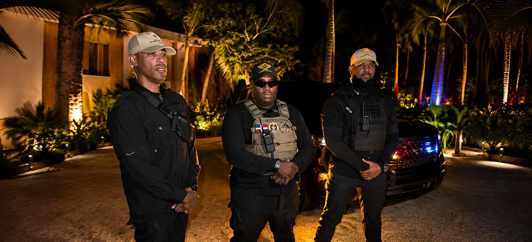 Nighttime security team standing in front of a luxury vehicle at a tropical property