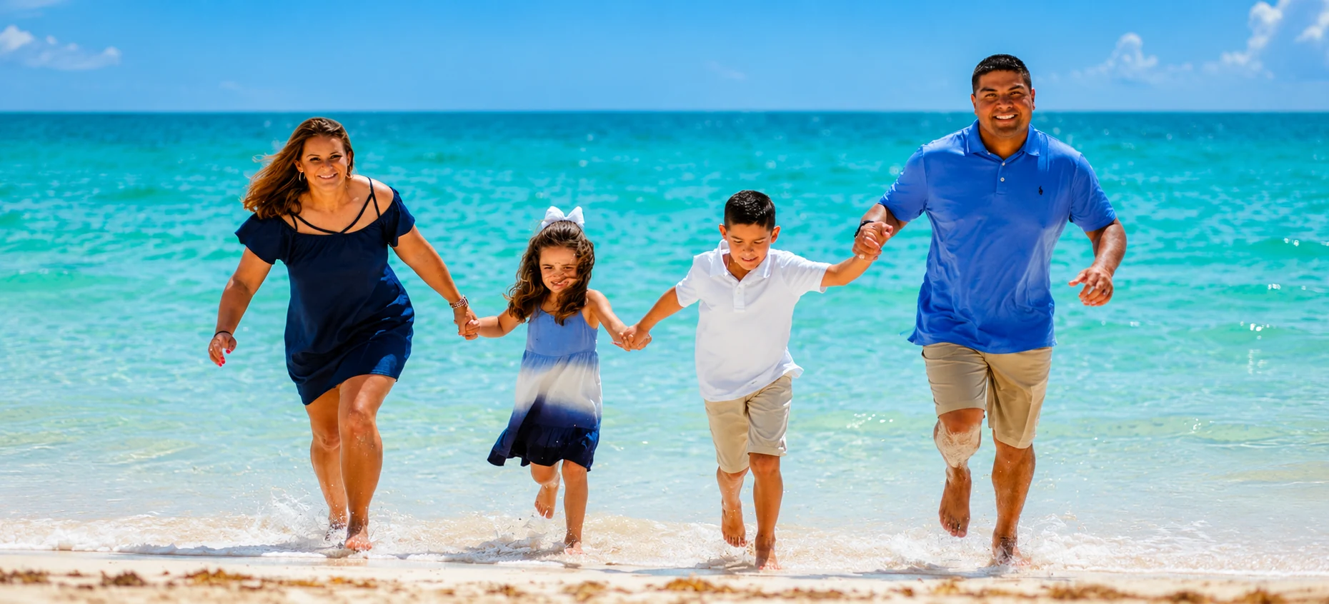 Family running together through shallow turquoise water on a sunny Punta Cana beach