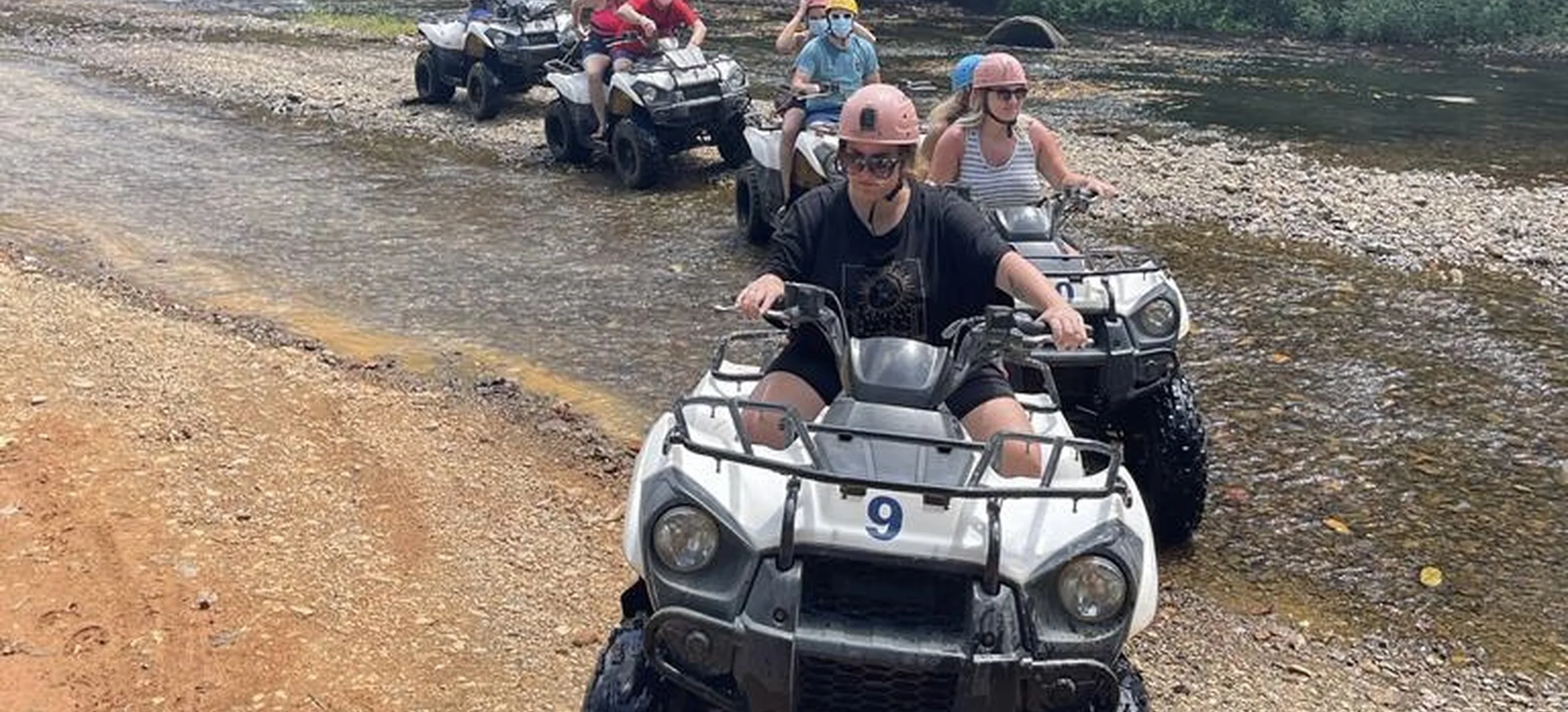 Group of ATV riders crossing a river during a Punta Cana countryside adventure.