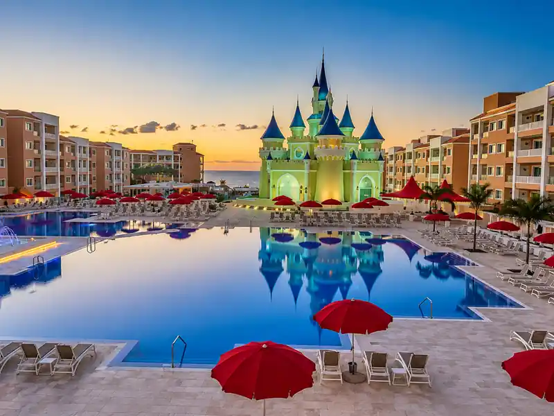Nickelodeon Punta Cana resort pool with castle and red umbrellas at sunset