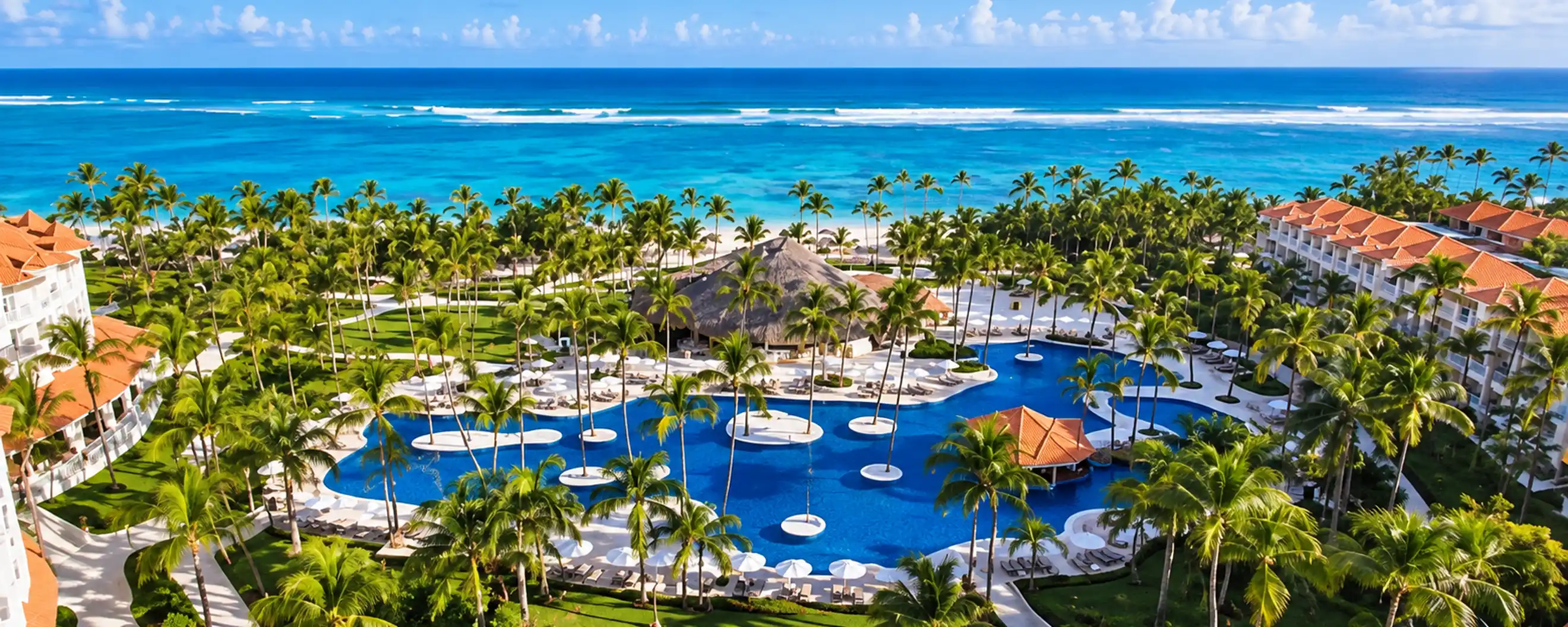 Aerial view of a beachfront Punta Cana resort with tropical pools, palm trees and Caribbean Sea