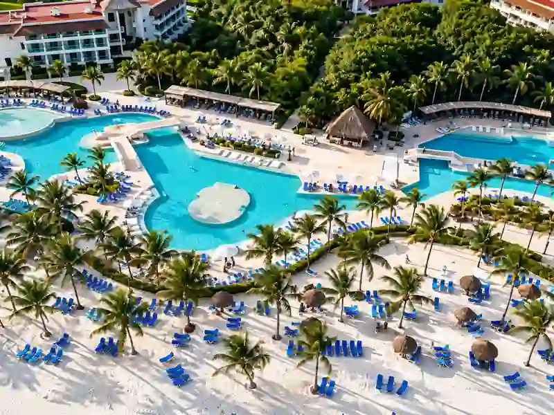 Aerial view of Punta Cana beachfront resort pools with palm trees and tropical gardens