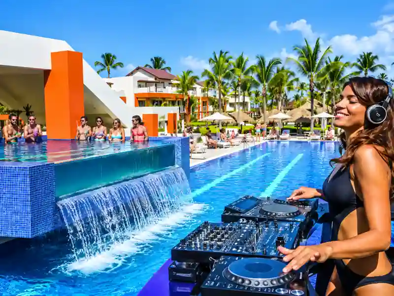 Punta Cana resort pool party with DJ, swim-up bar and tropical palm trees