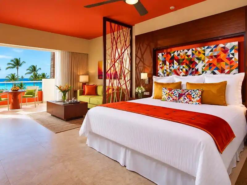 Luxury tropical resort suite with king bed, balcony and ocean view