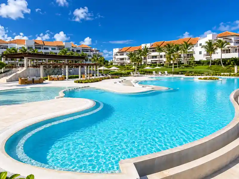 Luxury Punta Cana resort swimming pool surrounded by palm trees and tropical gardens
