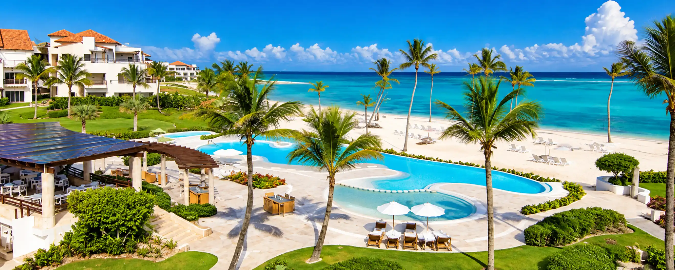 Luxury beachfront resort with tropical swimming pool, palm trees and turquoise Caribbean Sea in Punta Cana