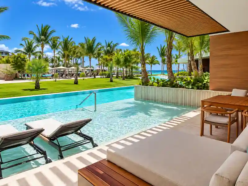Luxury Punta Cana swim-up suite with private pool terrace, palm trees and tropical resort view