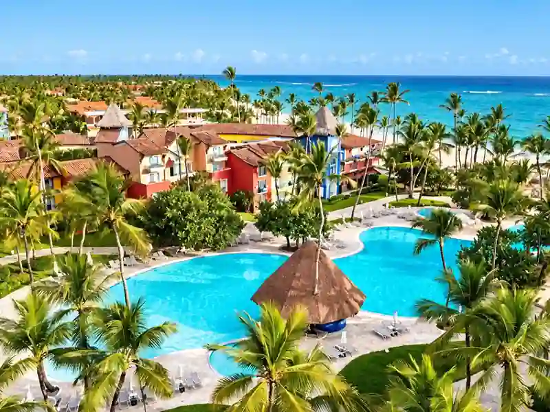 Caribe Deluxe Princess tropical swimming pool with palm trees and ocean views in Punta Cana.