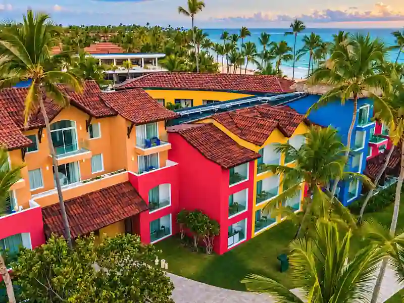 Colorful Caribe Deluxe Princess beachfront resort surrounded by palm trees in Punta Cana.