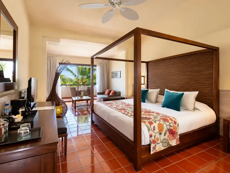 Catalonia Punta Cana deluxe resort room with canopy bed and tropical balcony view.