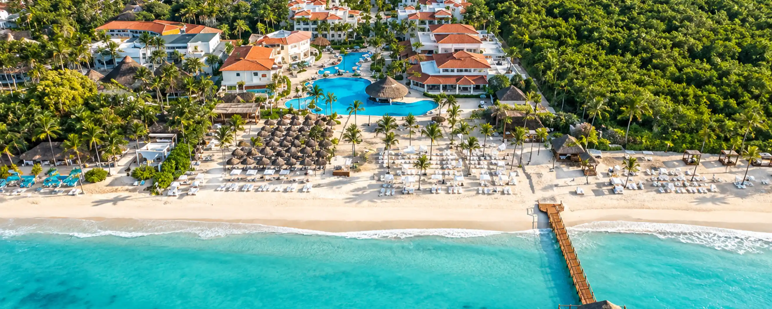 Aerial view of Dreams La Romana beachfront resort with turquoise Caribbean water and tropical pools