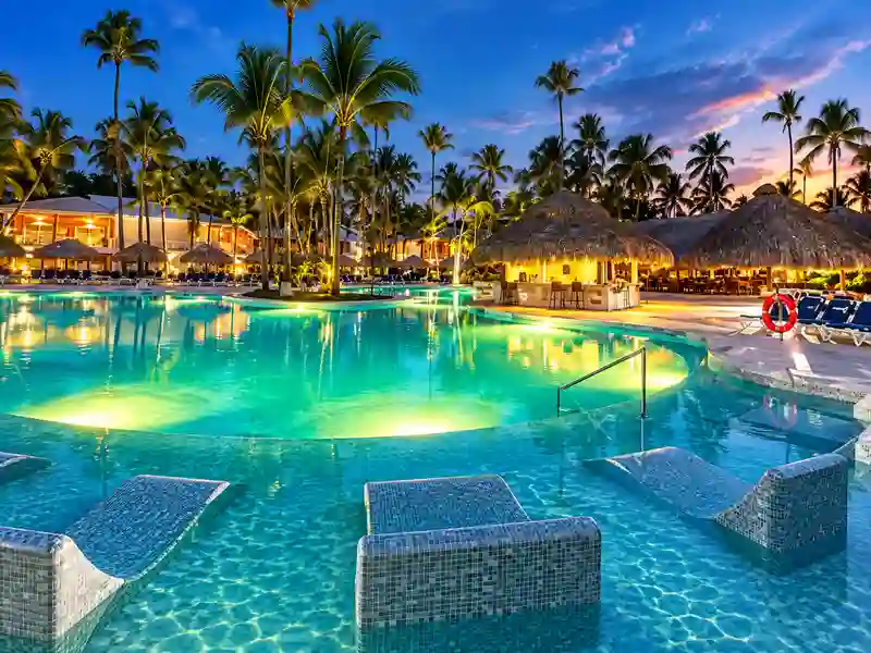 Grand Palladium Palace Resort Spa & Casino tropical swimming pool and palapa bar at sunset in Punta Cana