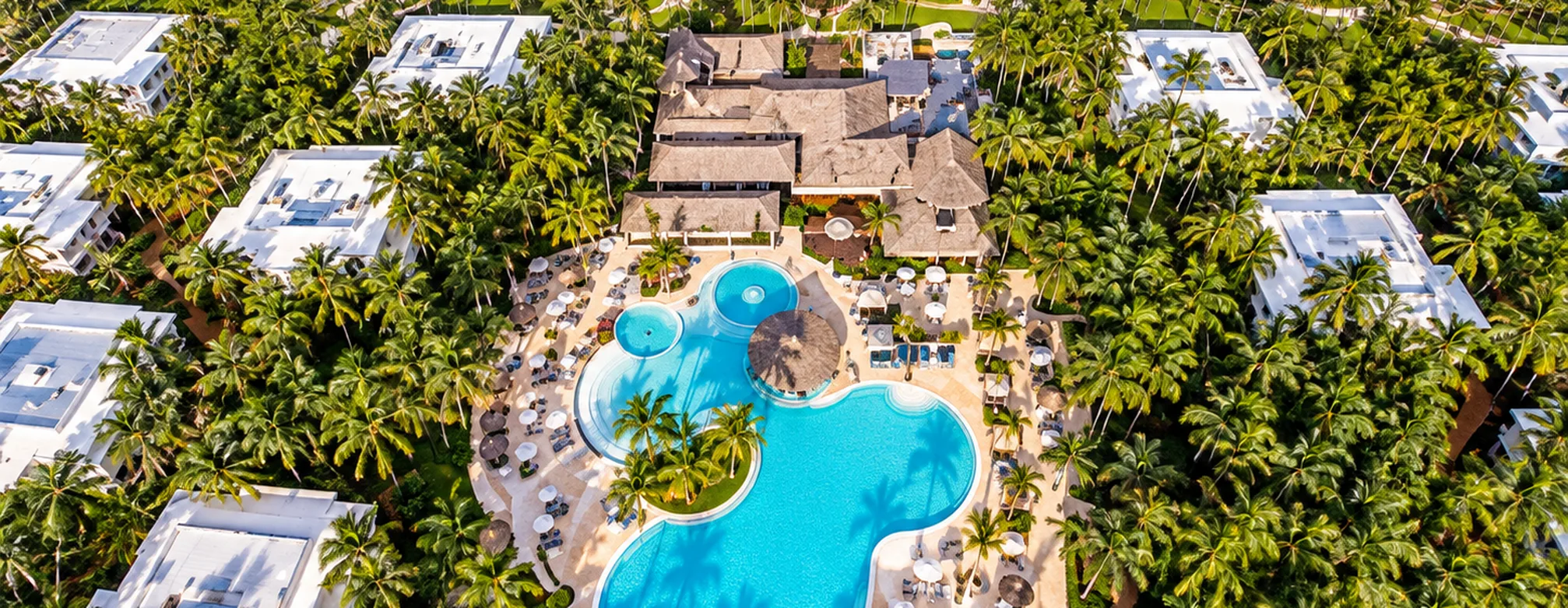 Aerial view of Grand Palladium Palace Resort Spa & Casino with tropical pool, palm trees and beachfront in Punta Cana